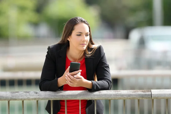 Fundersam verkställande håller en telefonen utomhus — Stockfoto
