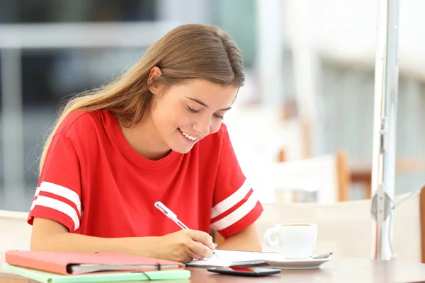 Heureuse étudiante prenant des notes dans un bar — Photo