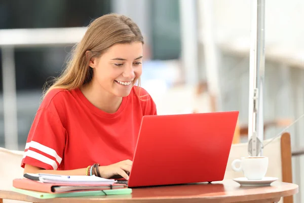 Estudante feliz digitando em um laptop em um bar — Fotografia de Stock