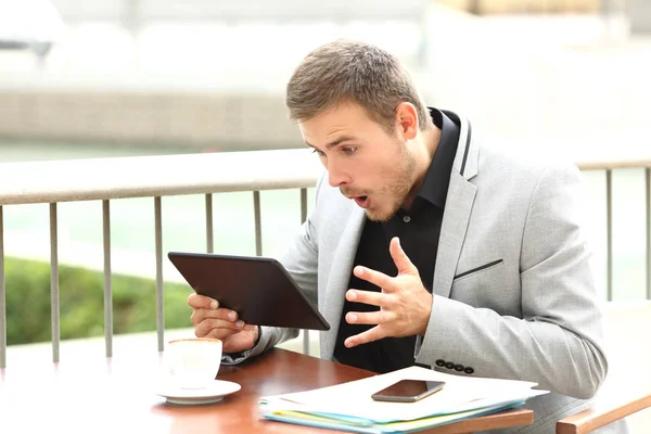Amazed executive reading surprising news in a tablet