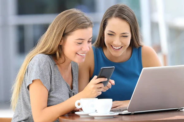 Två vänner dela en smart telefon i ett kafé — Stockfoto