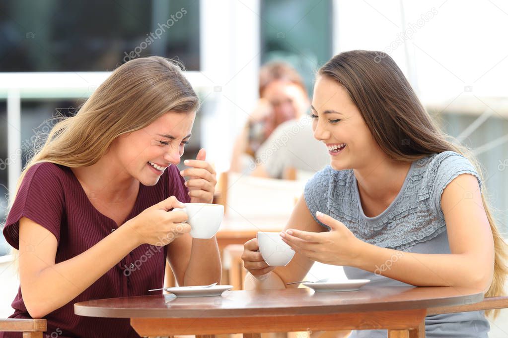 Best friends laughing loud during a conversation in a bar