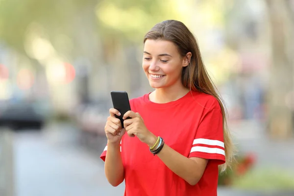 Feliz adolescente mensajes de texto en el teléfono en la calle — Foto de Stock