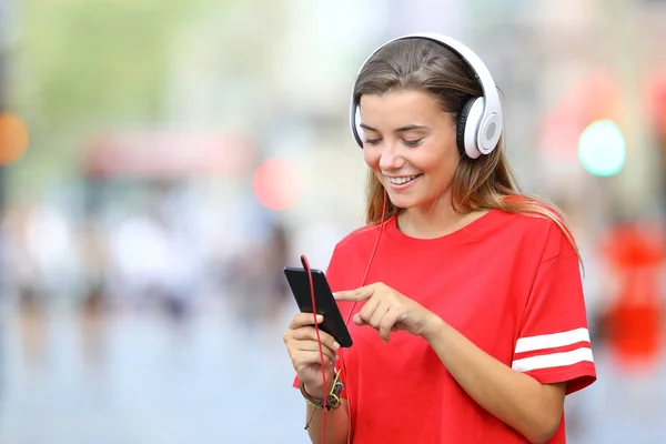 Adolescente in rosso ascoltare musica on line per strada — Foto Stock
