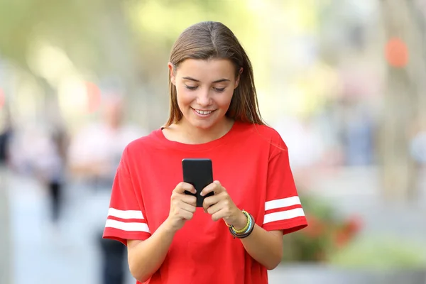 Vista frontal de um adolescente usando um telefone inteligente — Fotografia de Stock