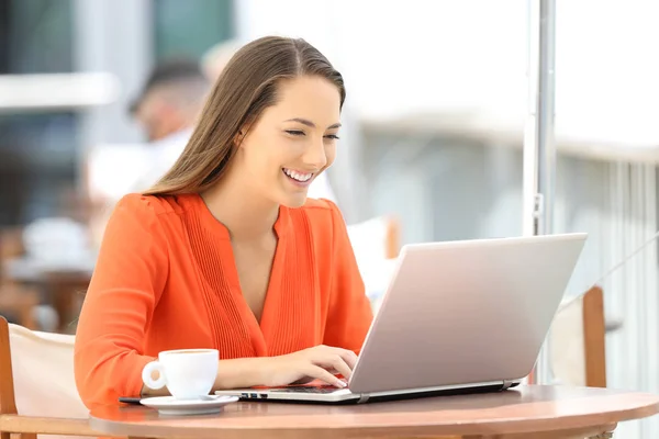 Lady em laranja digitando em um laptop em um restaurante — Fotografia de Stock