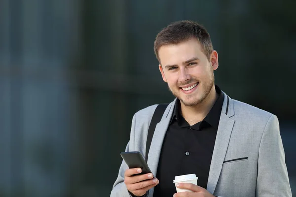 Zufriedener Manager mit einem Handy in der Hand, das in die Kamera schaut — Stockfoto