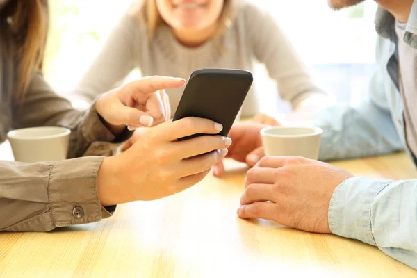 Tre amici che condividono uno smartphone in un bar — Foto Stock