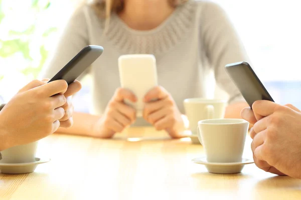 Tres amigos usando sus teléfonos inteligentes en un bar — Foto de Stock