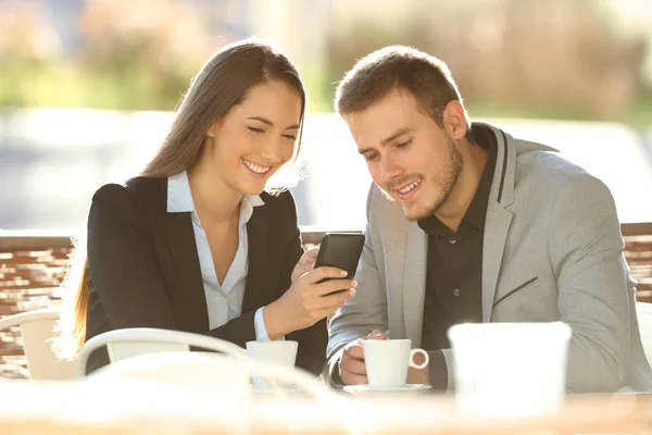 Dois executivos usando um telefone inteligente em uma cafeteria — Fotografia de Stock