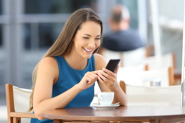 Mulher feliz usando um telefone inteligente em um terraço bar — Fotografia de Stock