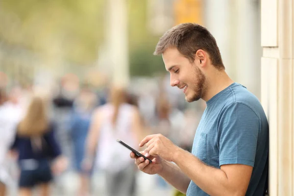 Profilo di un ragazzo felice che scrive su uno smartphone — Foto Stock