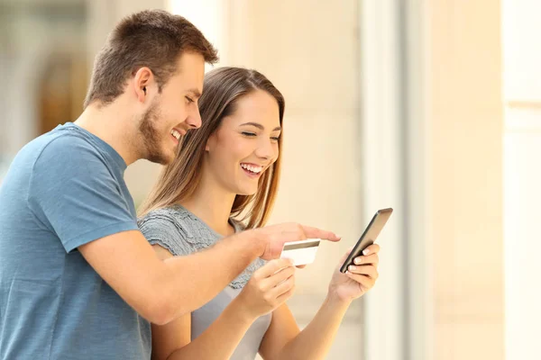 Pareja comprando en línea en frente de una tienda — Foto de Stock