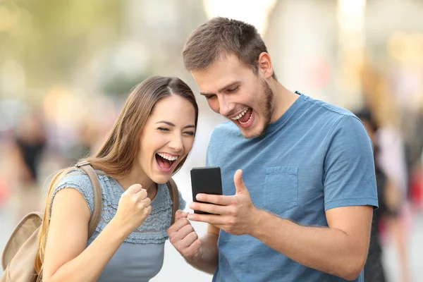 Emocionado casal recebendo boas notícias on-line fora — Fotografia de Stock