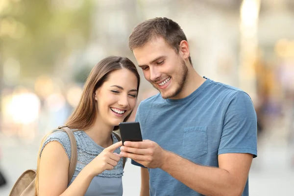 Casal feliz usando um telefone inteligente na rua — Fotografia de Stock