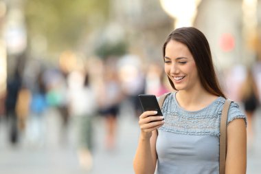 Mutlu kadın sokakta bir akıllı telefon ayakta kullanarak