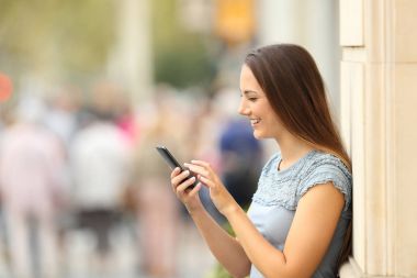 Sokakta bir akıllı telefon kontrol bir kız yan görünüm