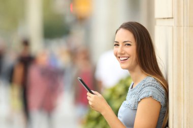 Sokakta kameraya bakarak akıllı telefon kullanıcı