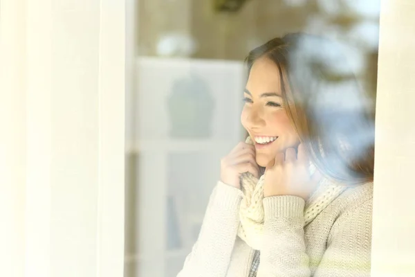 Femme heureuse regardant à travers une fenêtre en hiver — Photo
