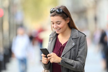 Moda kız sokakta bir akıllı telefon kullanarak ayakta