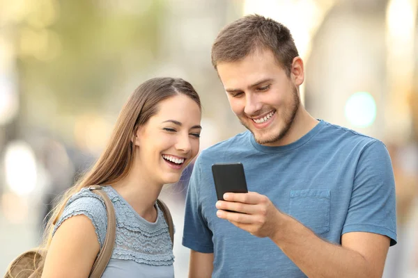 Couple enjoying using a smart phone on the street — Stock Photo, Image