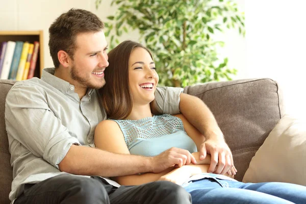 Счастливая пара сидит на диване и смотрит в сторону — стоковое фото