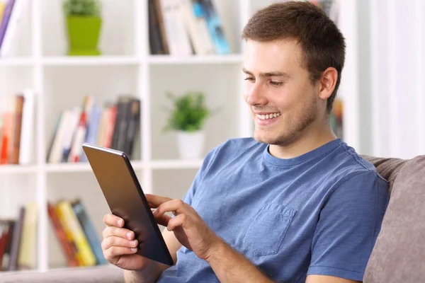 Homem usando um tablet em um sofá em casa — Fotografia de Stock