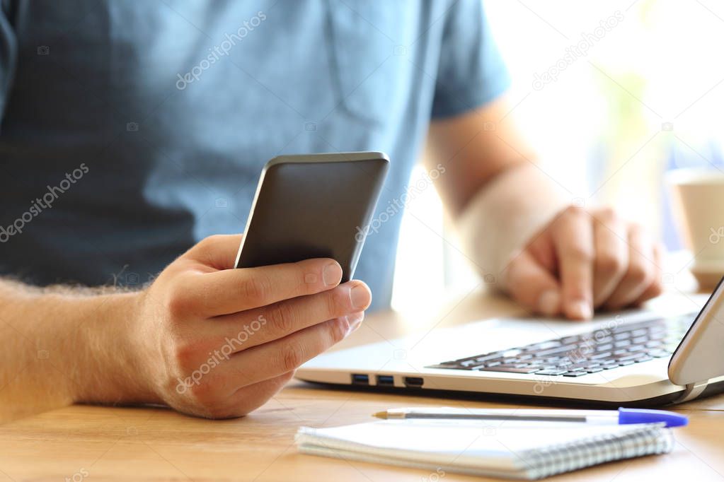 Man hands using a smart phone on a desktop