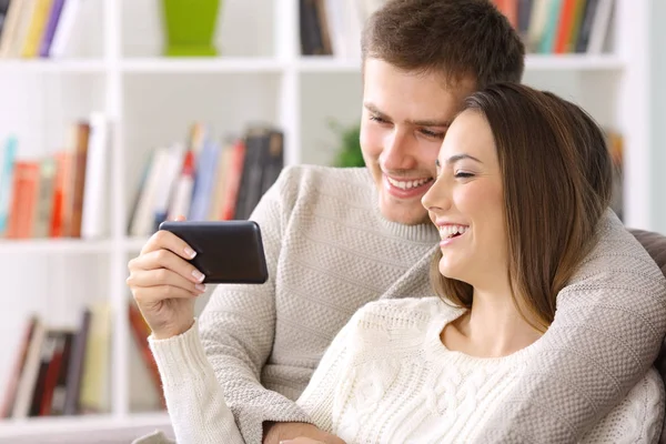 Pasangan yang menonton konten baris dalam telepon pintar di rumah — Stok Foto