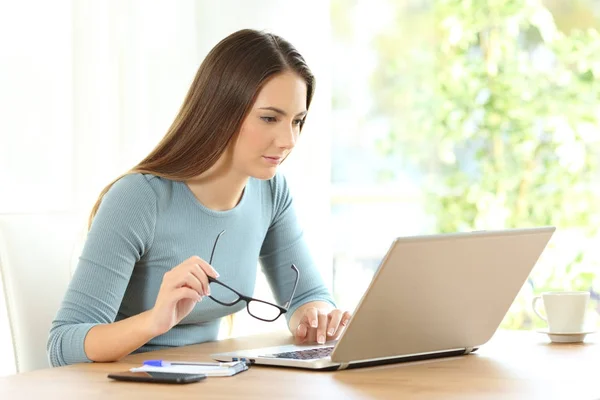Mulher segurando óculos usando um laptop — Fotografia de Stock