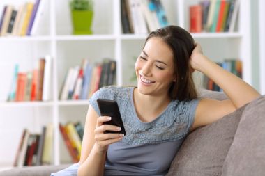 Evde kanepede bir akıllı telefon kullanan kız