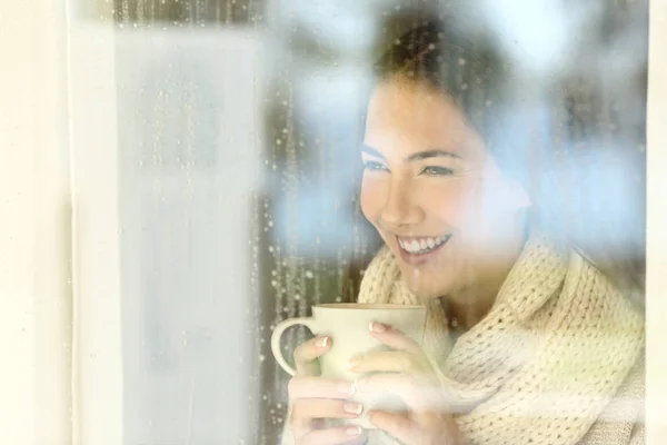 Szczęśliwa Pani patrząc przez okno w zimie — Zdjęcie stockowe