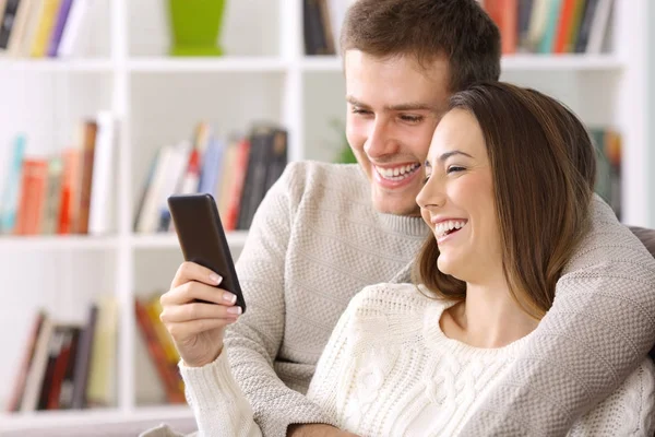 Casal usando um telefone inteligente em casa no inverno — Fotografia de Stock