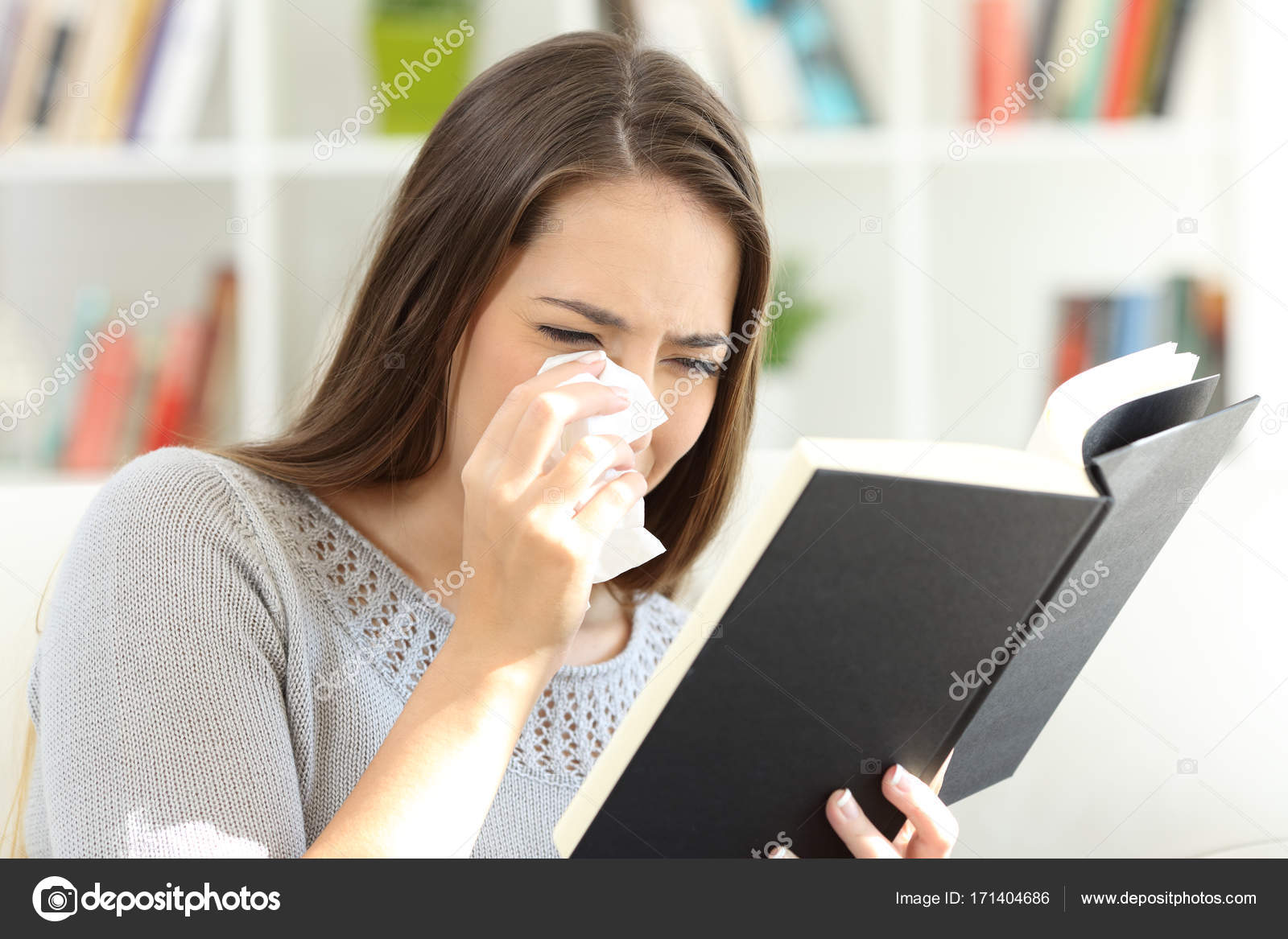 Woman crying while is reading a paper book at home Stock Photo by