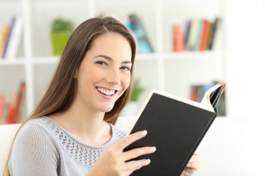 Bir kitap okuma ve kameraya bakarak kız