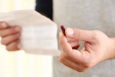 Adam bir hap tutarak ve broşür okuma eller