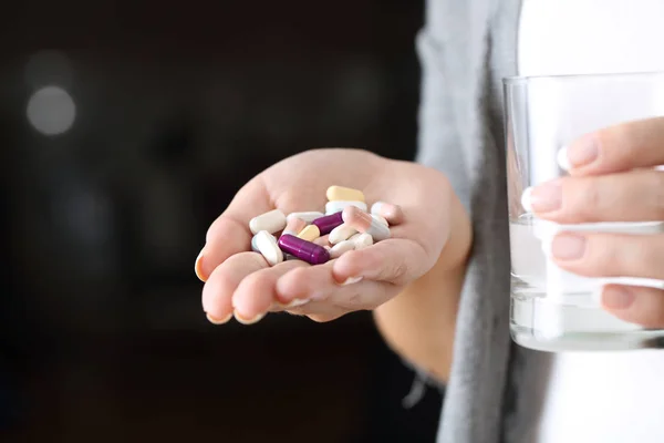 Женщина держит в руках много таблеток и стакан — стоковое фото