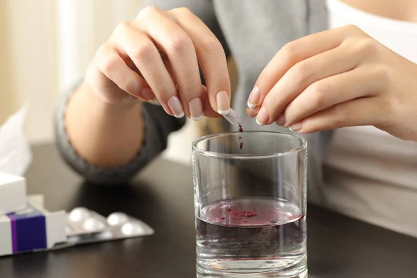 Le mani di donna che dissolvono un contenuto di capsula in acqua — Foto Stock