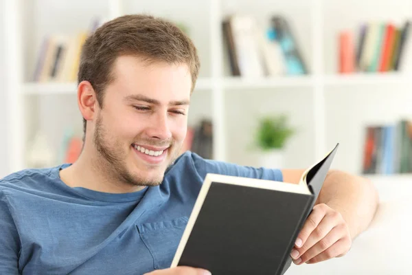 Happy man reading a paper book at home