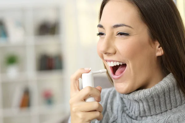 Vrouw met behulp van een pijnstillende spray — Stockfoto