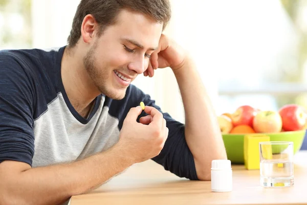 Hombre feliz tomando una píldora de vitaminas en casa —  Fotos de Stock