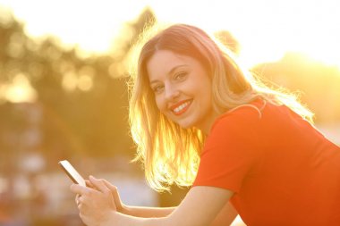 Gün batımında akıllı telefon ile mutlu kız