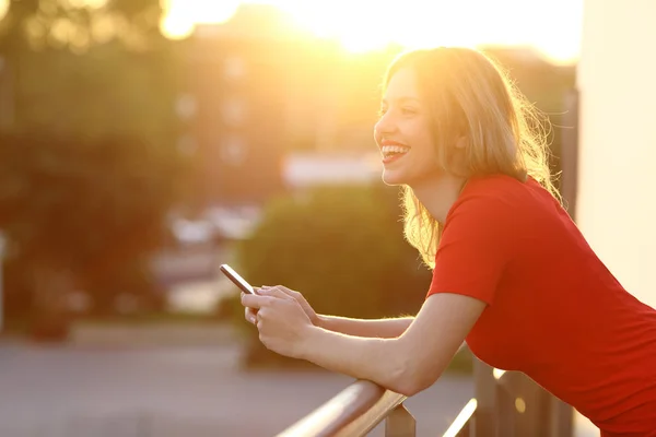 Fille penser et tenir un téléphone intelligent au coucher du soleil — Photo