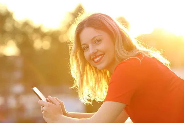 Chica feliz con teléfono inteligente al atardecer — Foto de Stock