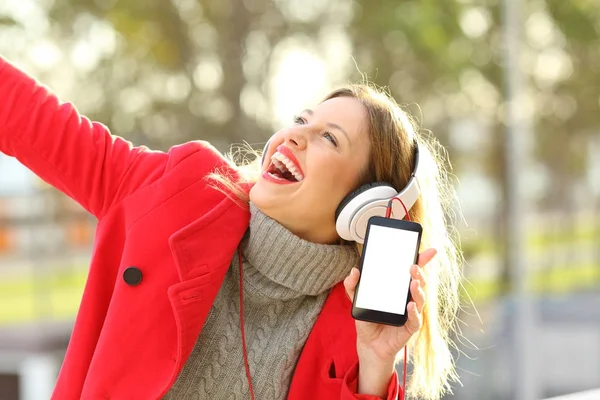 Glückliche Frau, die Musik hört und Handy zeigt — Stockfoto