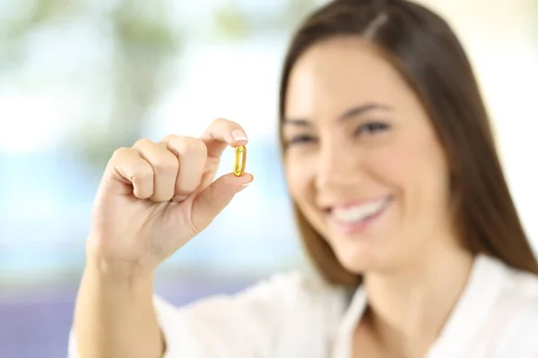 Mujer feliz mostrando una píldora omega 3 — Foto de Stock