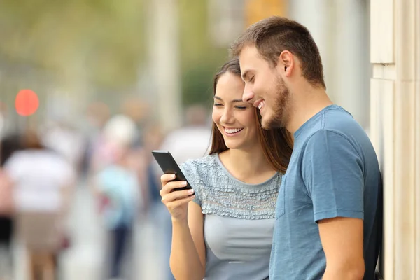 Casal assistindo na mídia on-line em um telefone inteligente na rua — Fotografia de Stock