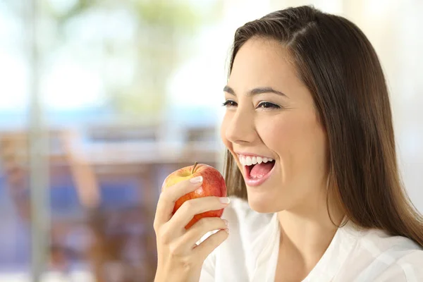 Женщина ест яблоко дома — стоковое фото
