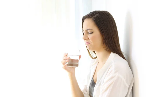 Mujer asqueada bebiendo agua con mal gusto en blanco — Foto de Stock