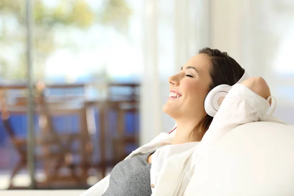 Chica feliz relajándose escuchando música en un sofá — Foto de Stock